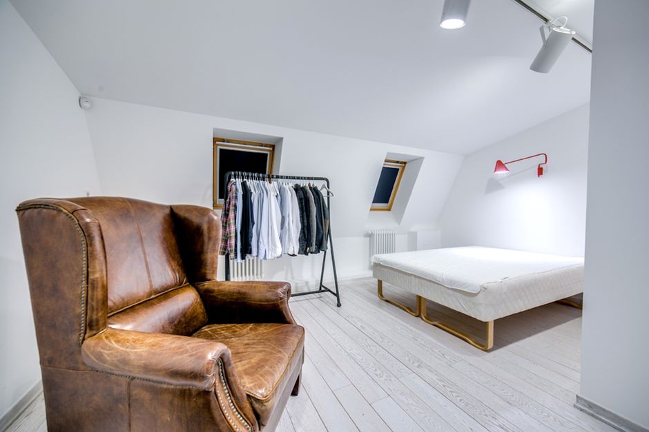 Inside a wooden storage shed with dark-stained timber walls and ceiling, a small, round ceiling light illuminates the space. Visible on a high shelf are several canisters of Cromar Cross-Seek sealant,